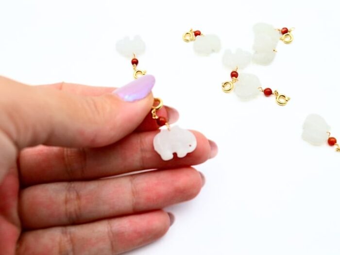 Pandantiv Feng Shui cu Elefant cu trompa in jos din Jad alb de aprox. 15 mm, bila de Coral rosu de 2 mm si accesorii aurii.